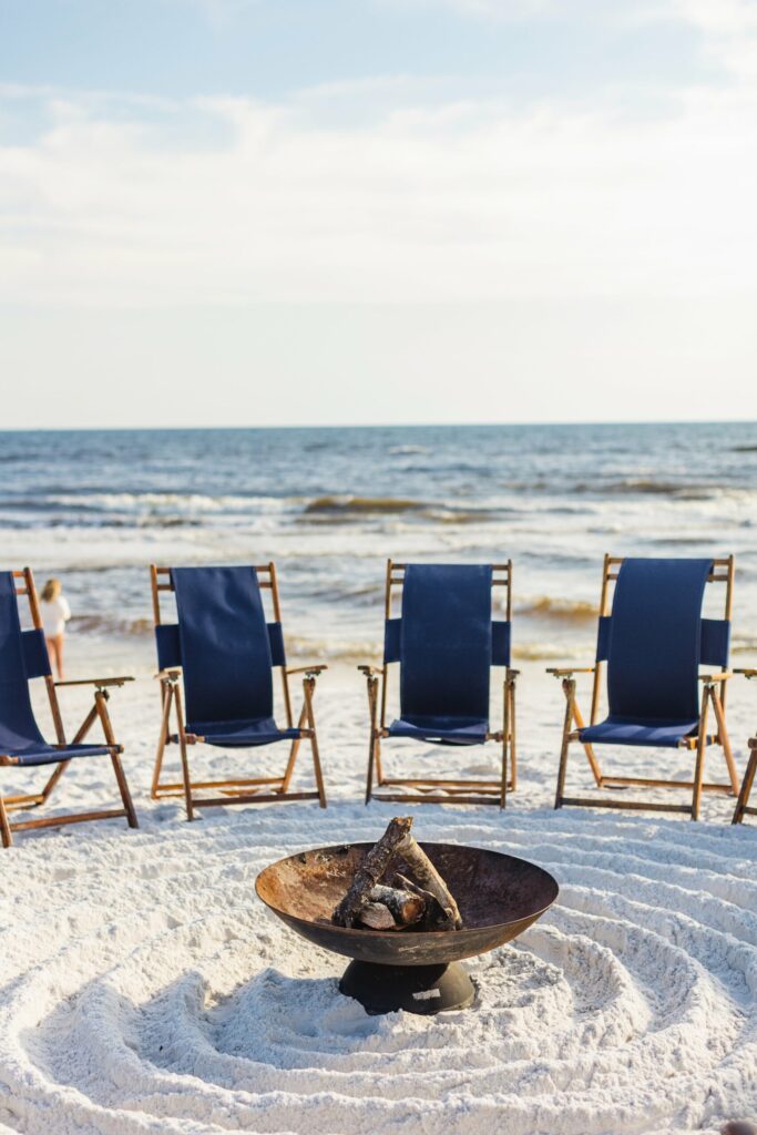 Beach bonfire with blue chairs.