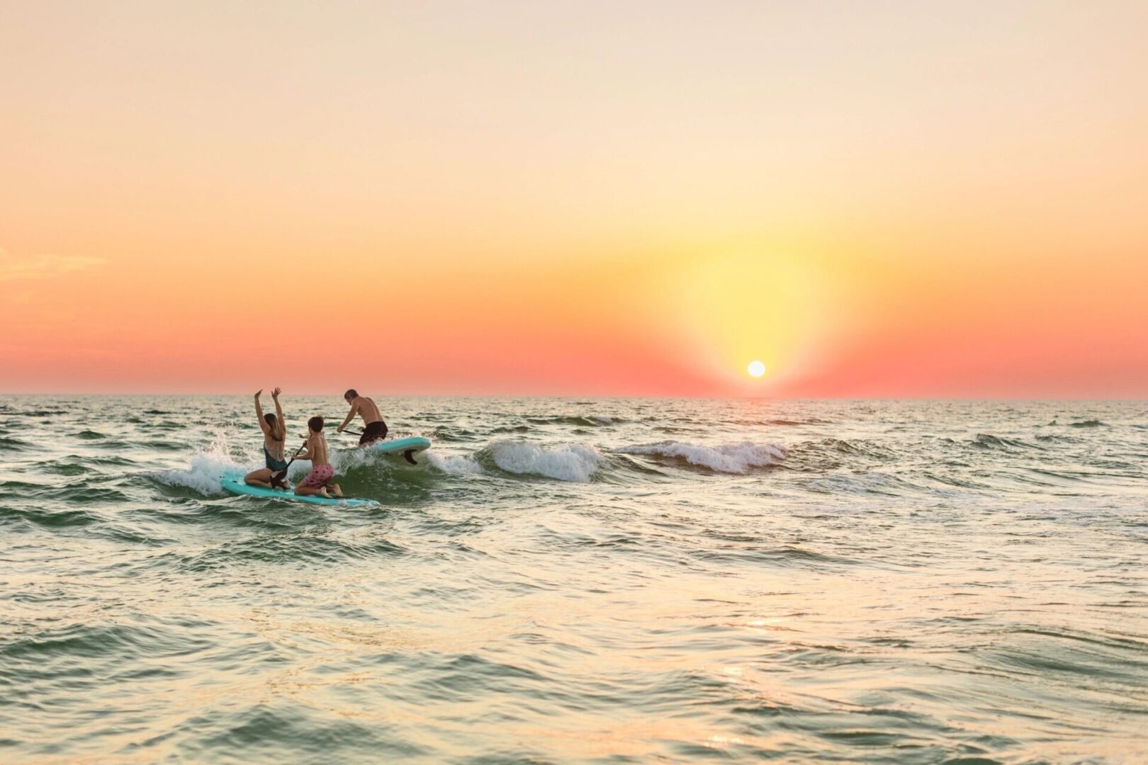 Surfers enjoying sunset waves on ocean.