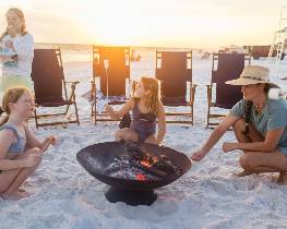 People gathered around beach fire pit at sunset