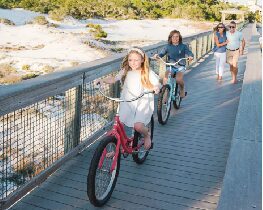 Kids biking on boardwalk by beach